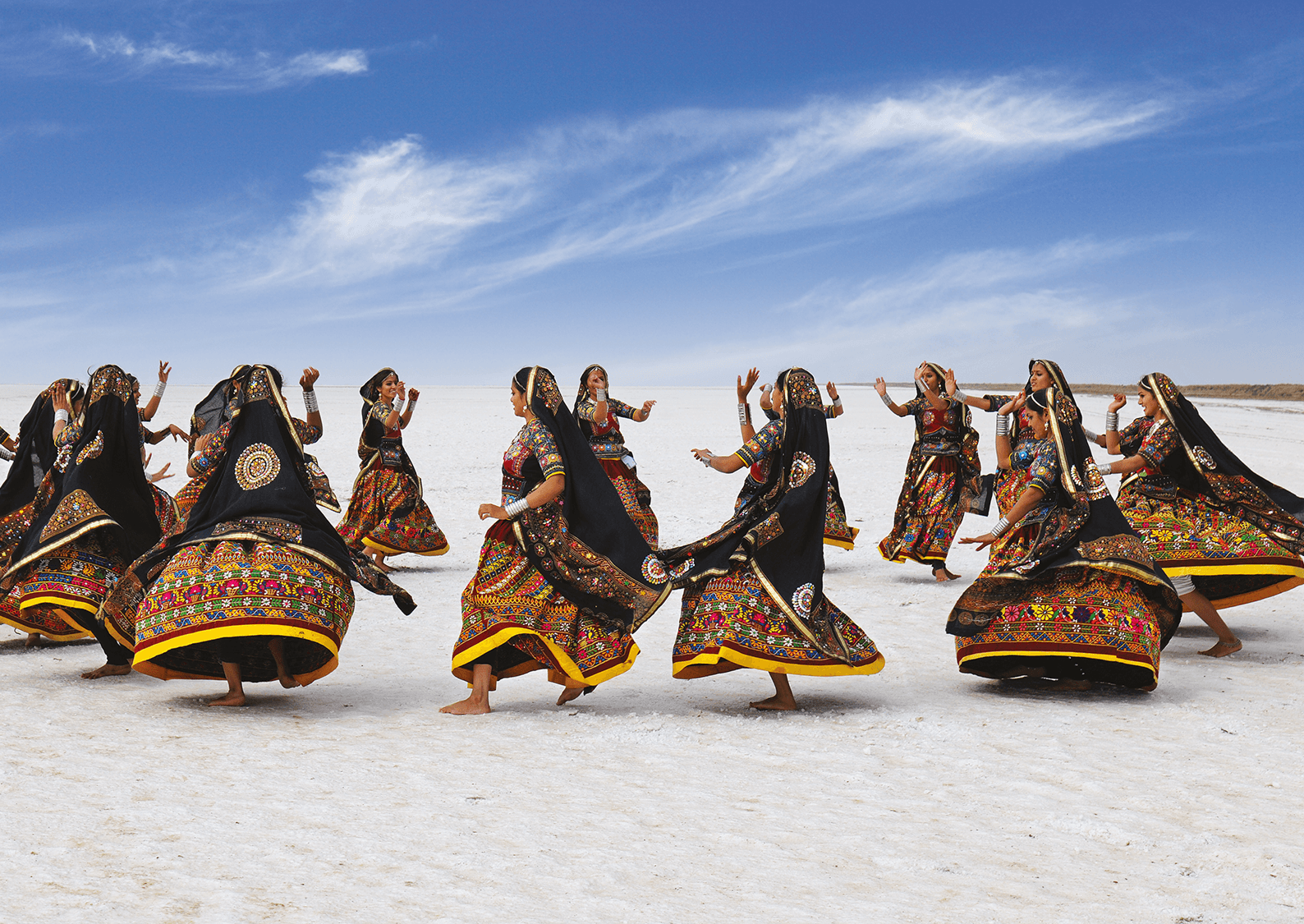 Women in traditional Kutchi dress performing Garba on the white salt flats
